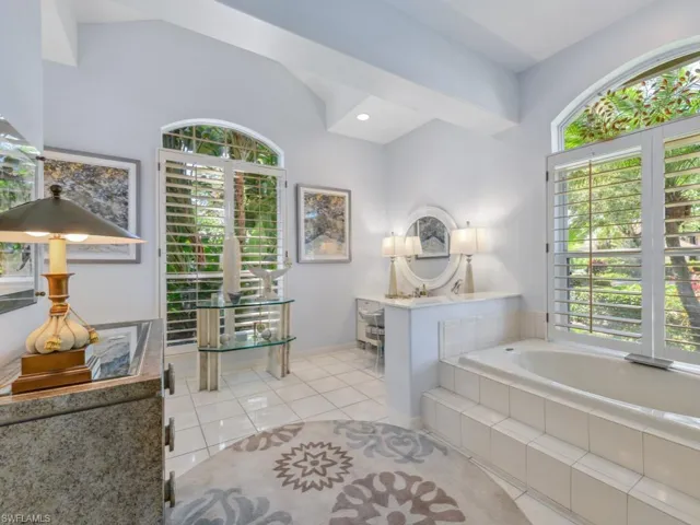 Bathroom featuring baseboards, lofted ceiling, a garden tub, and tile patterned flooring