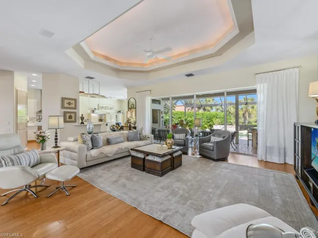 Living area with wood finished floors, visible vents, a raised ceiling, and ceiling fan
