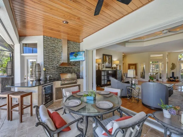 Dining space with beverage cooler, stone tile floors, wooden ceiling, and ceiling fan