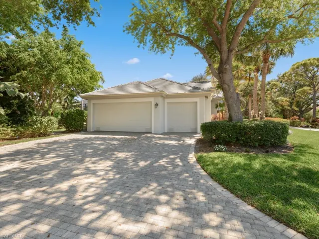 View of front of home with stucco siding, a front lawn, a garage, a tiled roof, and decorative driveway