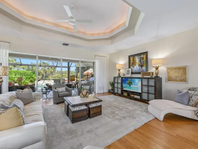 Living area featuring visible vents, a raised ceiling, wood finished floors, and a ceiling fan