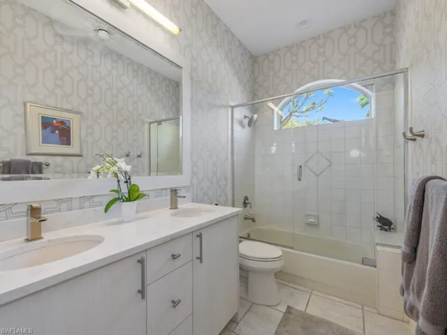 Full bathroom with a sink, enclosed tub / shower combo, and wallpapered walls