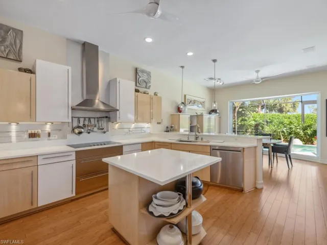 Kitchen featuring dishwasher, a peninsula, wall chimney exhaust hood, a ceiling fan, and a sink
