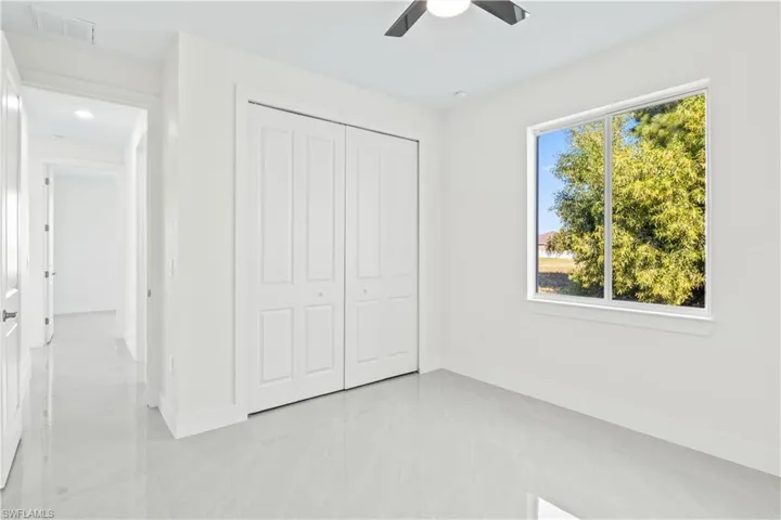 Unfurnished bedroom featuring a closet, a ceiling fan, and light tile patterned flooring