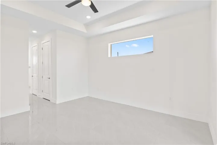 Spare room featuring a tray ceiling, recessed lighting, a ceiling fan, and light tile patterned flooring