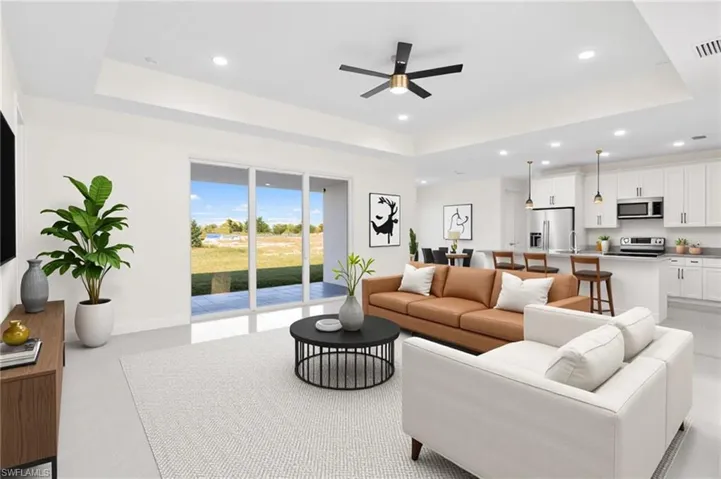 Living area with a raised ceiling, recessed lighting, and ceiling fan