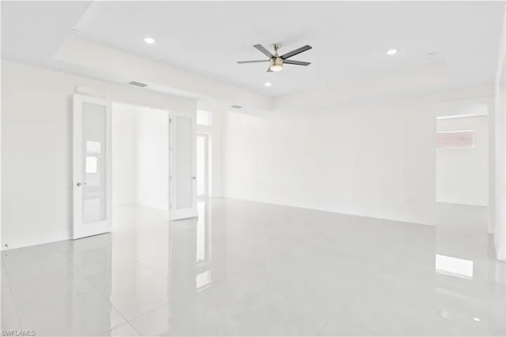 Spare room featuring a raised ceiling, light tile patterned floors, a ceiling fan, and recessed lighting