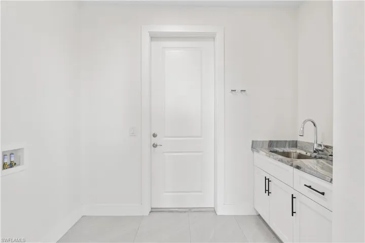 Laundry area featuring light tile patterned floors, washer hookup, and cabinet space