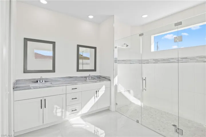 Full bathroom with double vanity, a stall shower, and recessed lighting