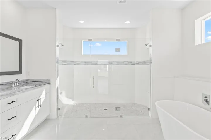 Bathroom featuring a freestanding bath, a stall shower, vanity, and recessed lighting