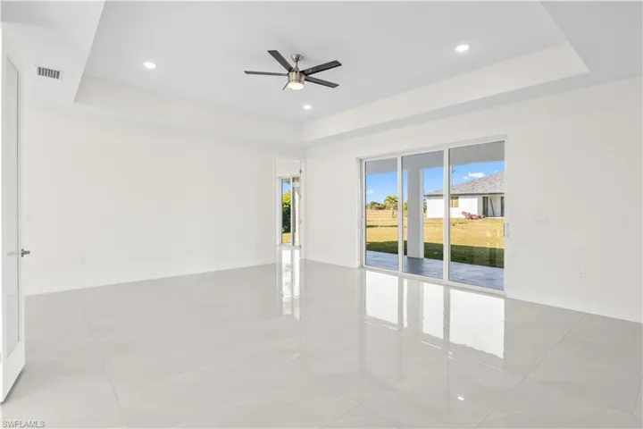 Unfurnished room with a tray ceiling, recessed lighting, light tile patterned floors, and a ceiling fan