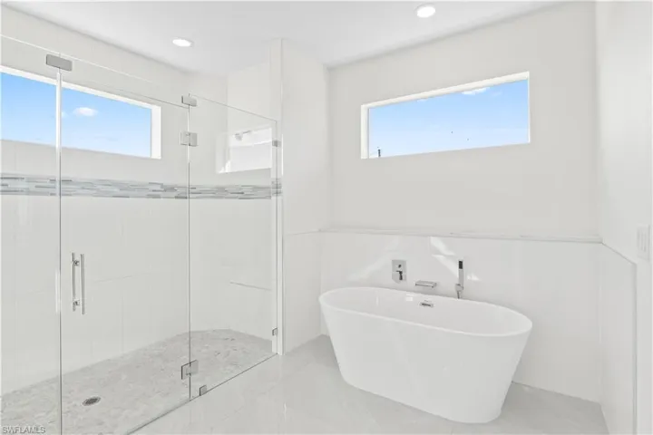 Bathroom featuring a freestanding tub, a stall shower, tile walls, recessed lighting, and marble finish floors