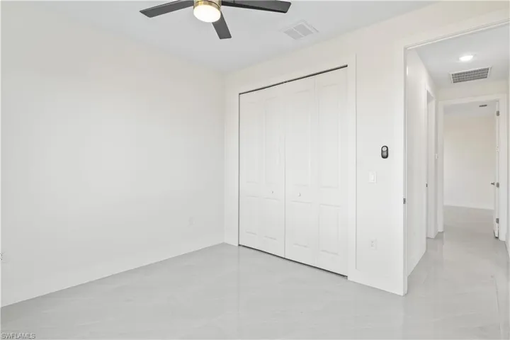 Unfurnished bedroom with ceiling fan and a closet