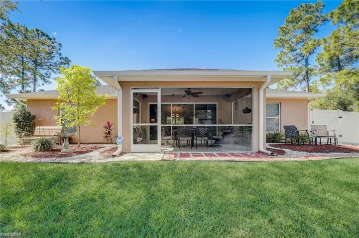Rear view of house with a sunroom, stucco siding, ceiling fan, and a gate