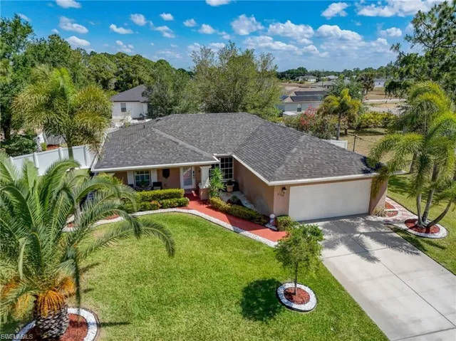 View of front of house featuring a garage, concrete driveway, stucco siding, a front lawn, and a shingled roof