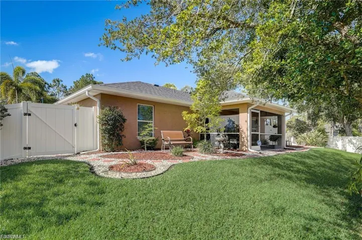 Rear view of house featuring a gate, stucco siding, a sunroom, a patio area, and a shingled roof