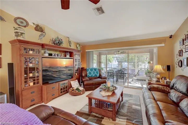 Living room featuring carpet, ceiling fan, and lofted ceiling