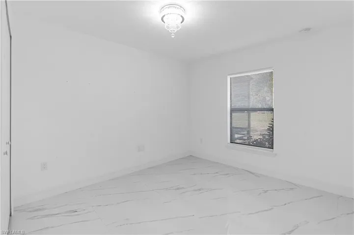 Empty room featuring light marble finish flooring and baseboards