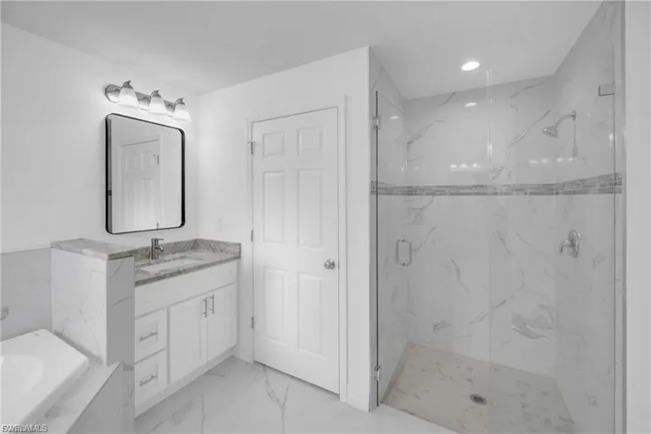 Bathroom featuring a marble finish shower, vanity, light marble finish flooring, recessed lighting, and a tub