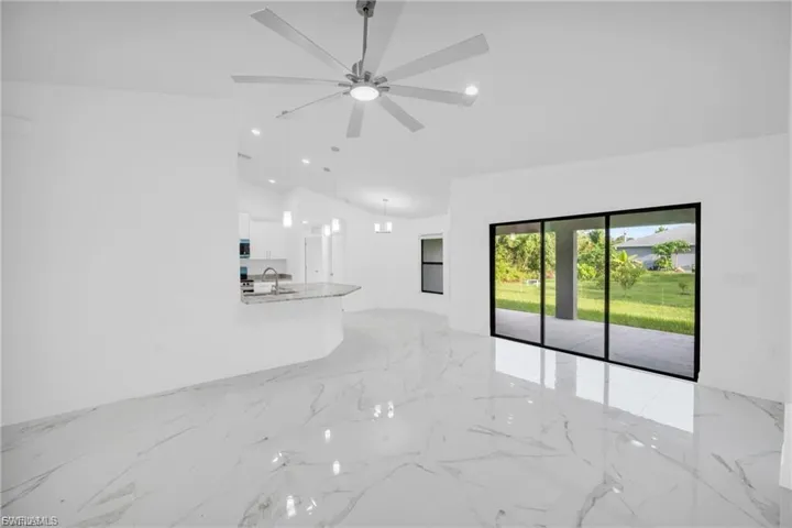 Unfurnished living room featuring lofted ceiling, light marble finish floors, and recessed lighting