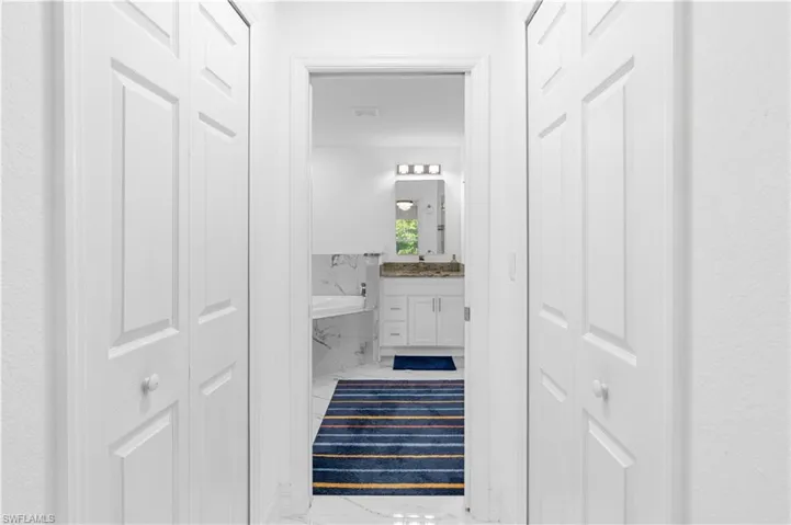 Full bathroom with a closet, vanity, a bath, and marble look tiles