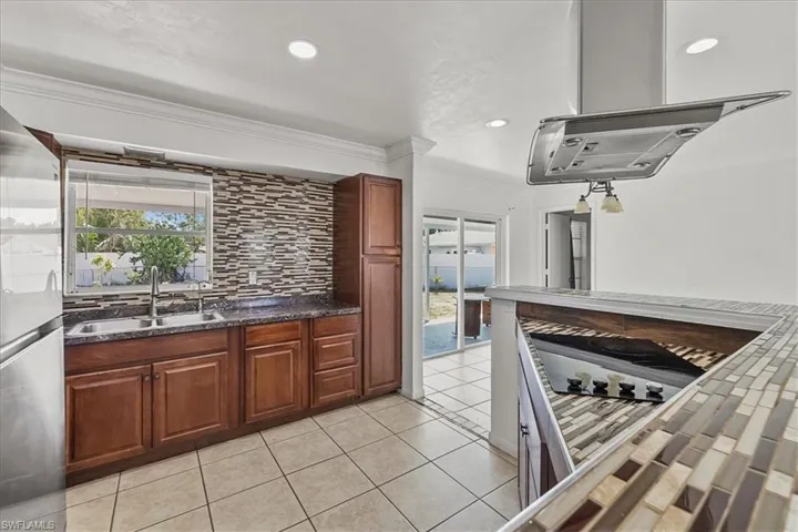 Kitchen with ornamental molding, a healthy amount of sunlight, decorative backsplash, and a sink
