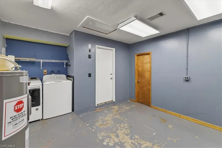 Below grade area with washing machine and clothes dryer, baseboards, visible vents, and water heater