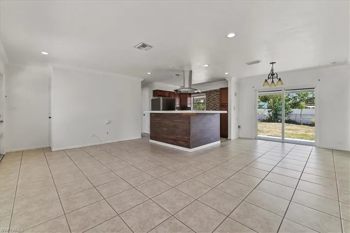 Unfurnished living room featuring ornamental molding, light tile patterned flooring, and visible vents