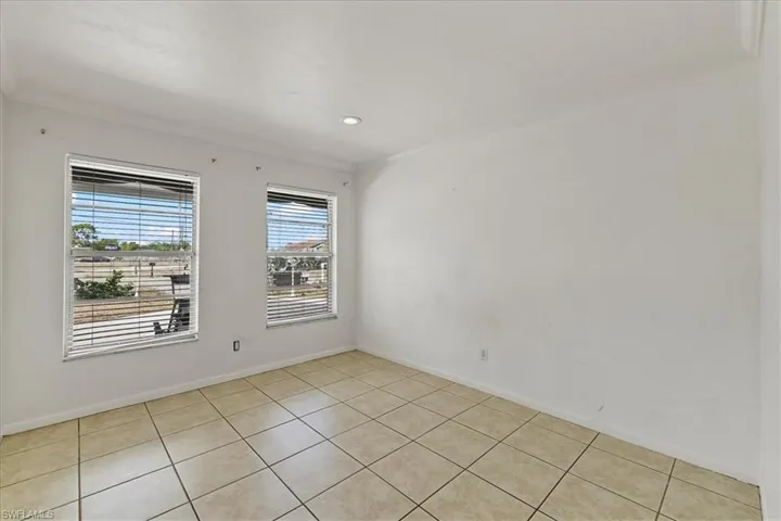 Spare room with ornamental molding, light tile patterned flooring, and baseboards