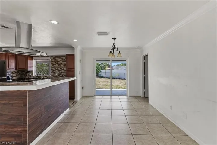 Kitchen featuring ornamental molding, island exhaust hood, tasteful backsplash, and a healthy amount of sunlight