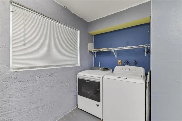 Clothes washing area with separate washer and dryer, laundry area, and a textured wall