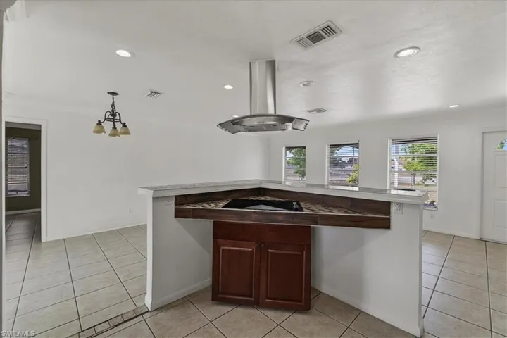 Kitchen with visible vents, island range hood, and light tile patterned flooring