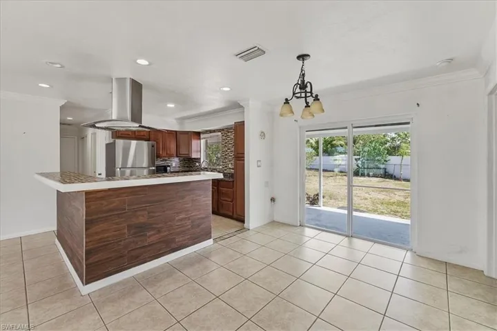 Kitchen featuring freestanding refrigerator, recessed lighting, visible vents, and crown molding
