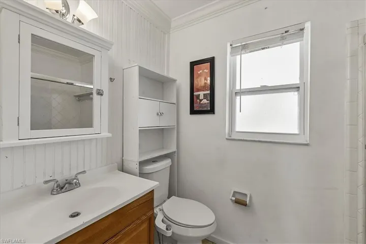 Bathroom with toilet, baseboards, ornamental molding, walk in shower, and vanity