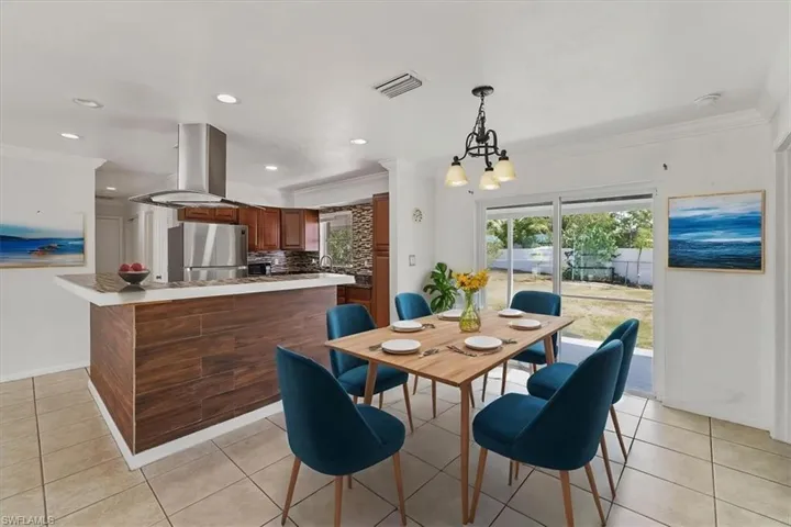Dining space with an inviting chandelier, light tile patterned floors, visible vents, ornamental molding, and recessed lighting