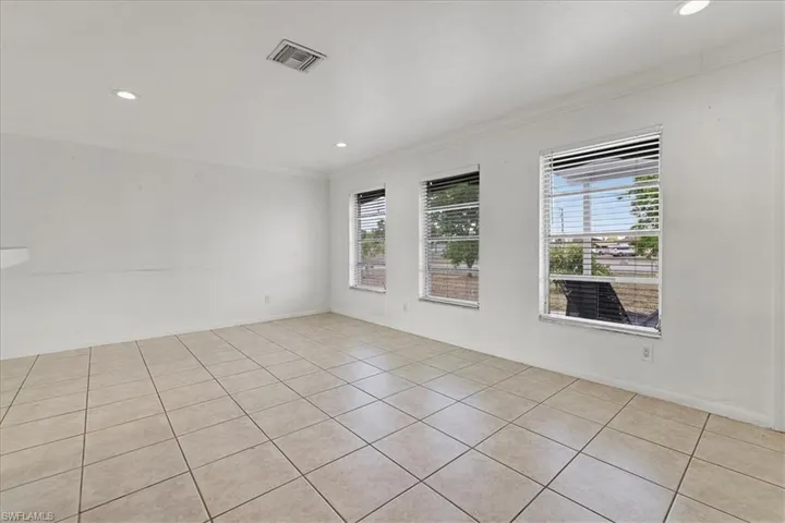 Empty room featuring light tile patterned floors, visible vents, ornamental molding, and recessed lighting