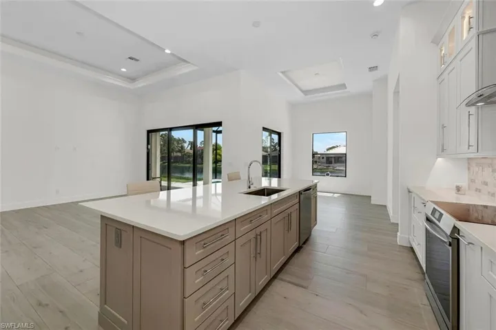 Kitchen cabinet design with lighted upper cabinets, stainless steel dishwasher, light wood-plank flooring, accent colored island pull-out cabinets and pull down faucet.