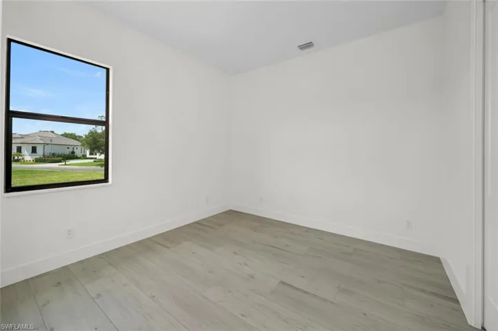 11'-6" x 11'-2" second bedroom with light wood-style plank flooring. Pool bath is just outside the bedroom door.