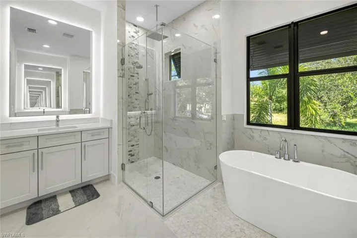 Bathroom featuring tile walls, independent shower and bath, tile patterned floors, and vanity