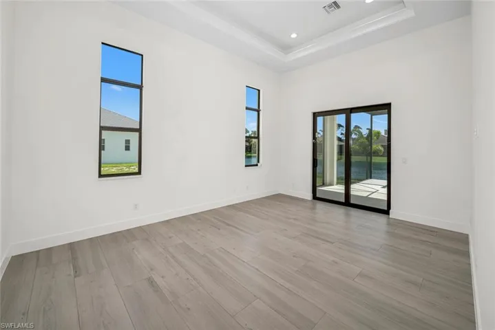 Unfurnished room featuring light hardwood / wood-style floors and a raised ceiling