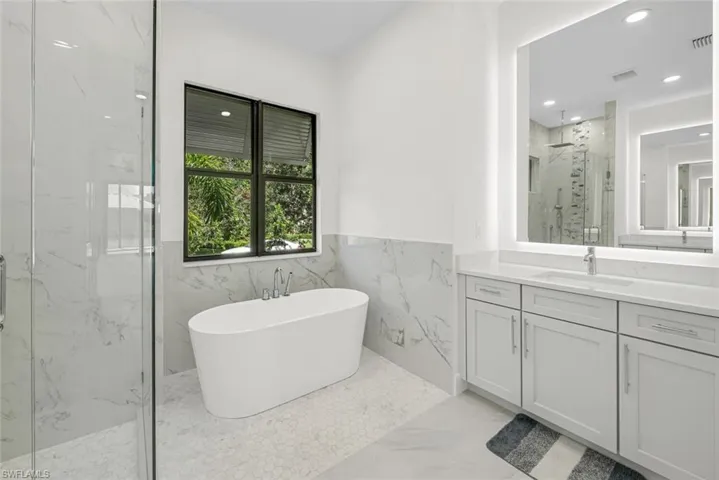 Bathroom with vanity, tile walls, tile patterned floors, and separate shower and tub