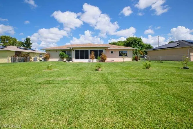 Back of property with a lawn and solar panels