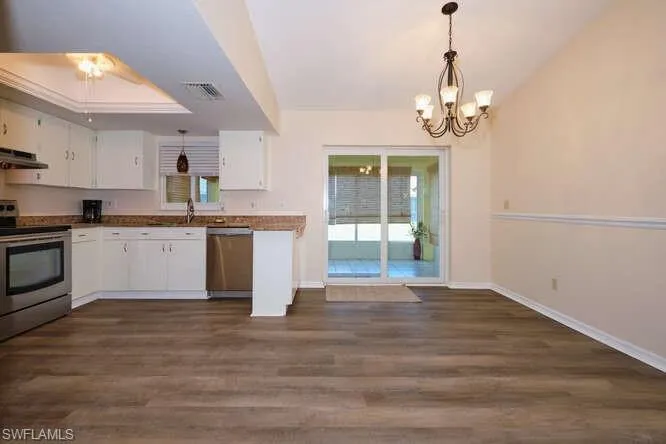 Kitchen featuring stainless steel appliances, dark hardwood / wood-style flooring, and white cabinetry
