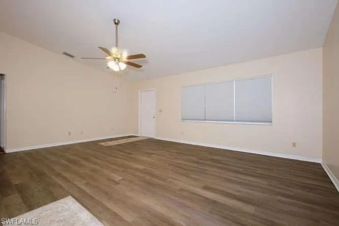 Empty room featuring ceiling fan, hardwood / wood-style flooring, and vaulted ceiling