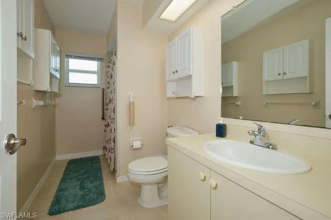 Bathroom featuring tile patterned floors, walk in shower, toilet, and vanity