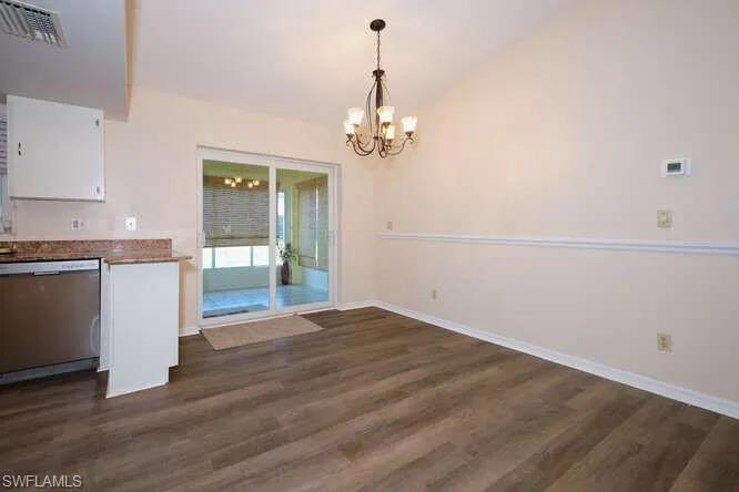 Unfurnished dining area with dark hardwood / wood-style flooring, a chandelier, and lofted ceiling