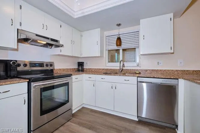 Kitchen featuring white cabinets, crown molding, appliances with stainless steel finishes, sink, and dark hardwood / wood-style floors
