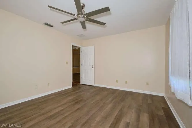 Empty room with dark wood-type flooring and ceiling fan