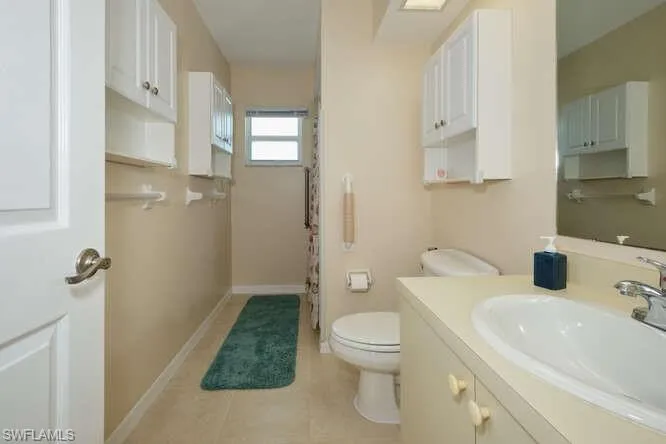 Bathroom featuring a shower with shower curtain, vanity, toilet, and tile patterned floors