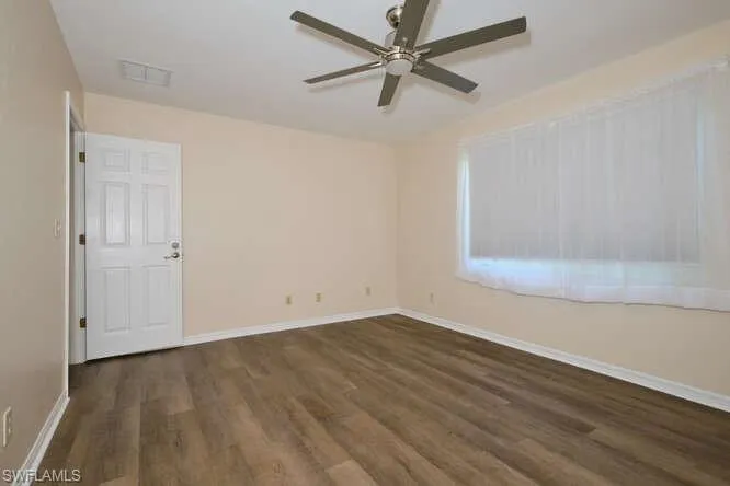 Unfurnished room featuring ceiling fan and dark hardwood / wood-style floors